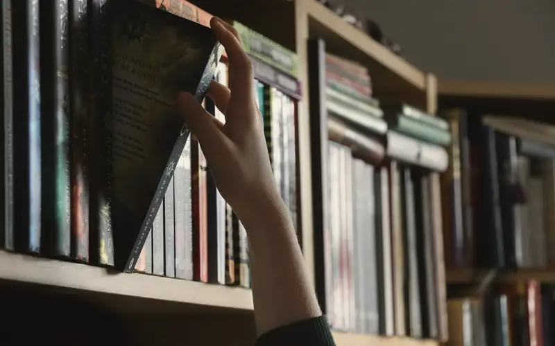 Hand die een boek uit de kast pakt