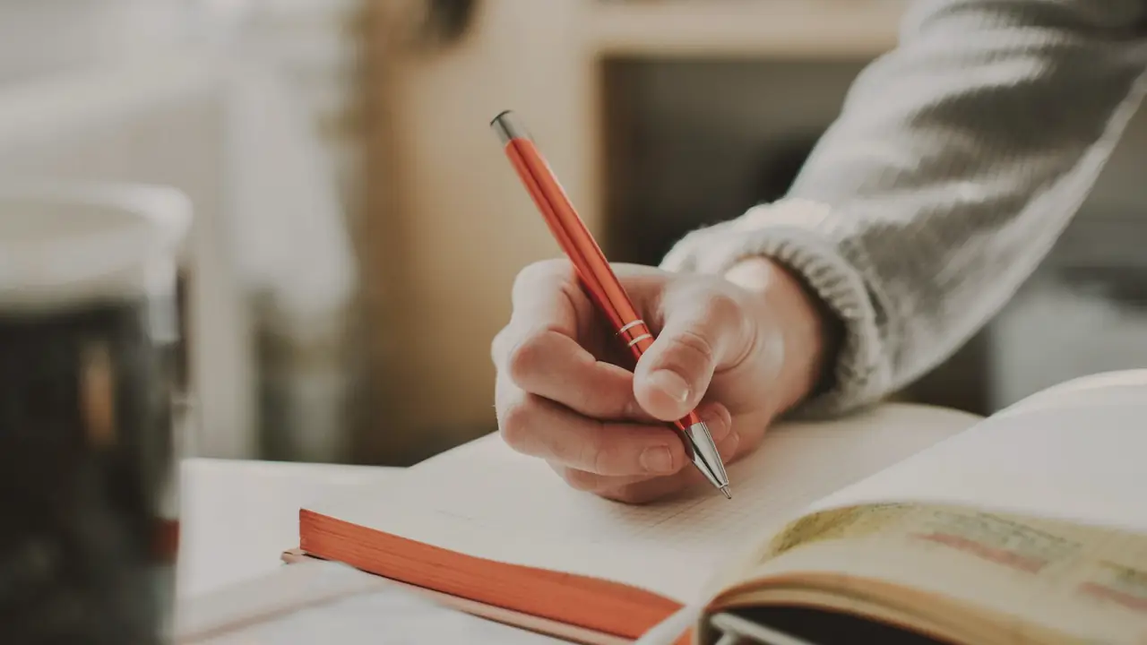 Hand die schrijft in een notitieboek